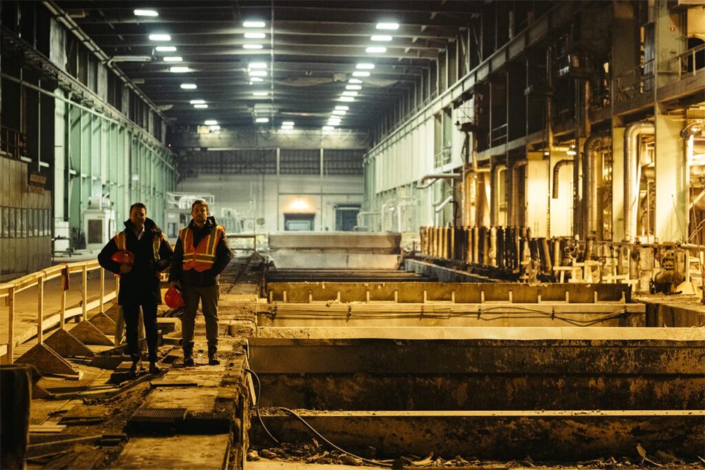 Two men standing in a large facility with safety gear